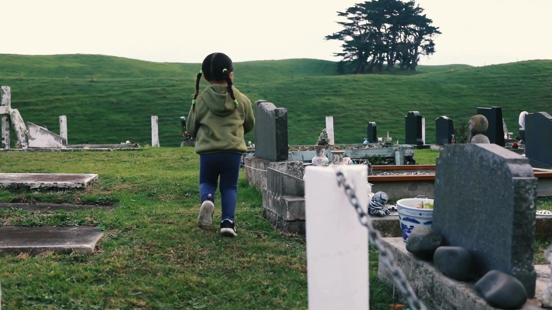 A child walking through a cemetery among headstones