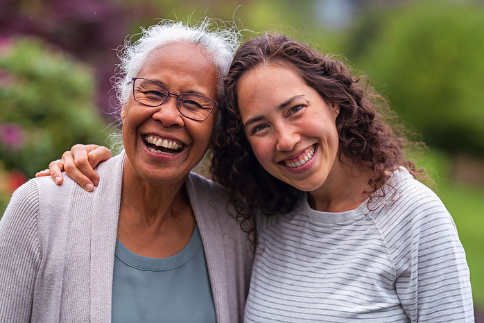 A grandmother and granddaughter embracing, smiling