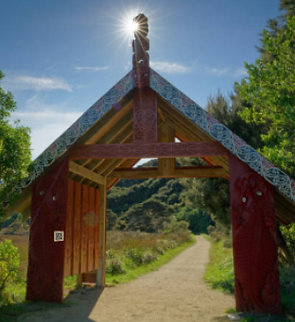 A carved wooden marae gateway with a QR plaque